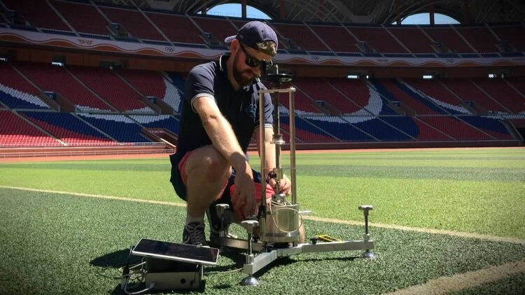 Sports Labs technician operating a surface test rig on an artificial pitch inside a stadium