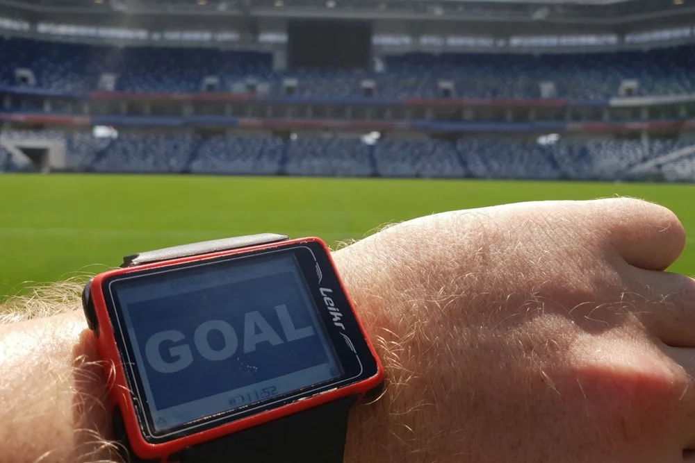 Referee watch displaying a GOAL alert from goal line technology inside a stadium