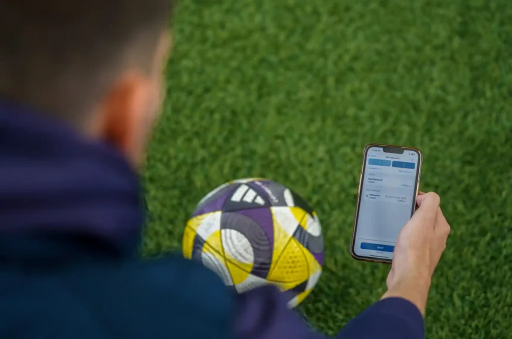 Sports Labs technician holding a football and recording test results on a handheld device