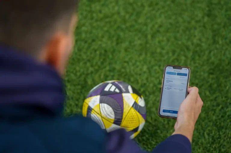 Sports Labs technician holding a football and recording test results on a handheld device