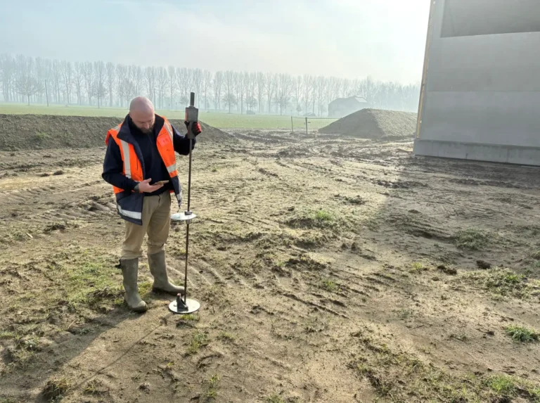 Surveyor in high visibility clothing recording levels on a pitch construction site