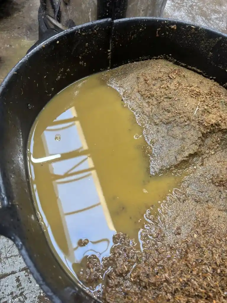 Bucket of sand infill sampled from a 3G pitch with cloudy, fines-laden water separating above it
