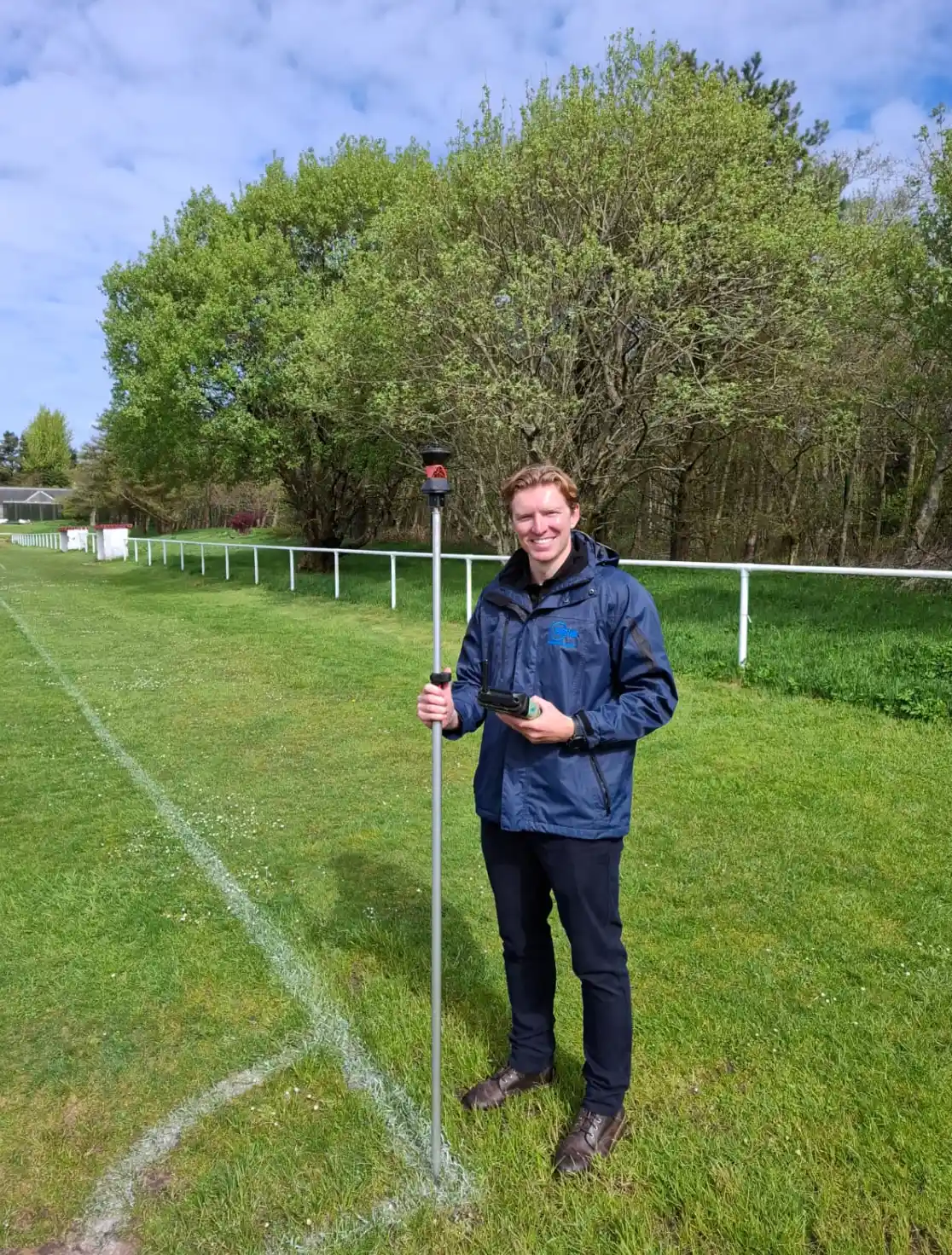 Sports Labs technician standing on a marked natural turf pitch