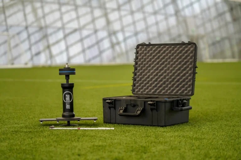 Prism Gauge set up on artificial grass next to its open protective carry case