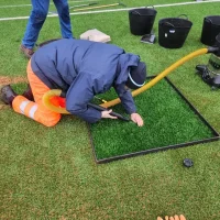 Sports Labs technician vacuuming performance infill from a marked test square on a 3G pitch to retest drainage